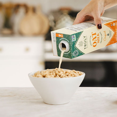 oat milk being poured on top of a ceral